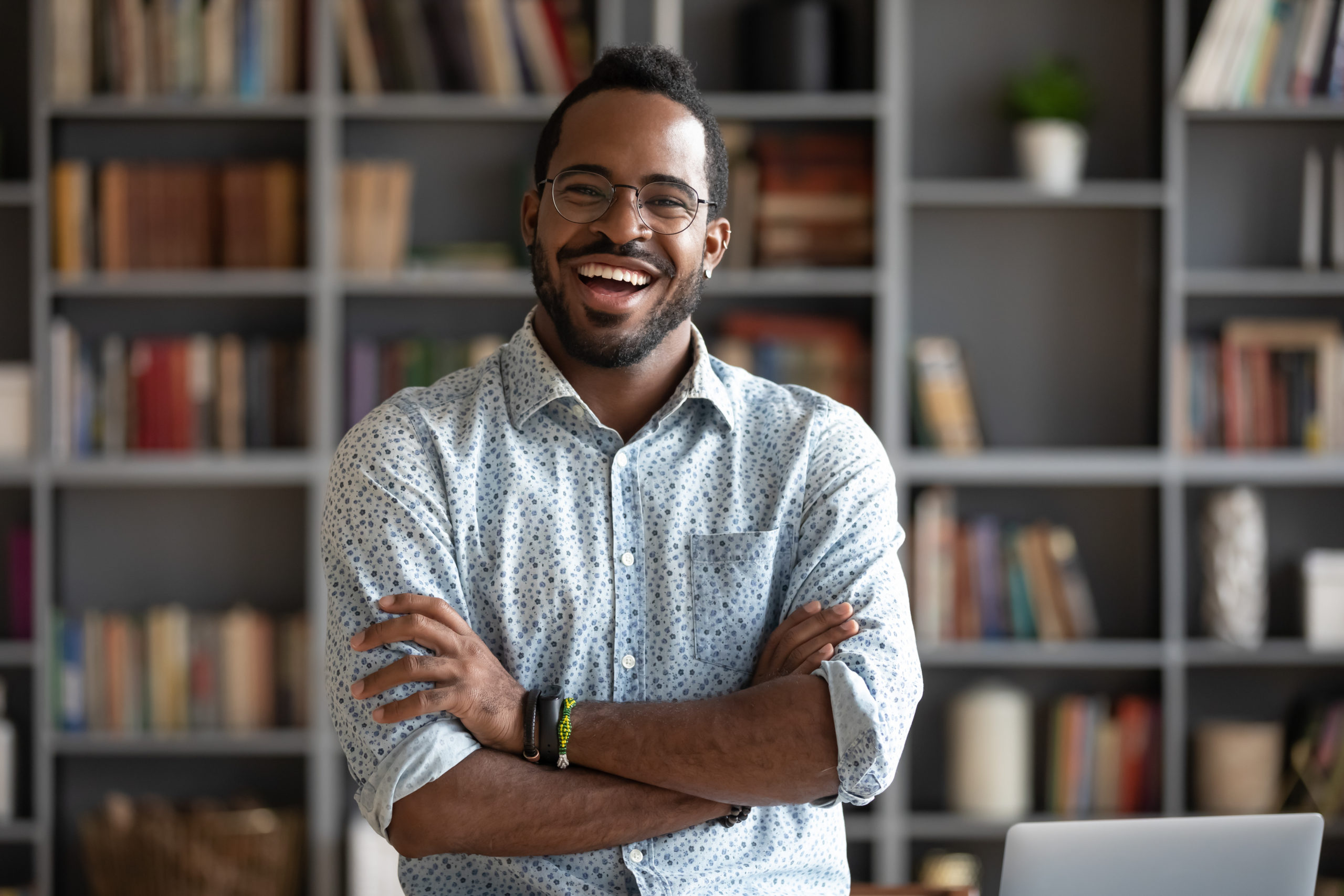Cheerful confident handsome african american young adult businessman professional teacher hipster entrepreneur laughing looking at camera standing arms crossed at home office, business portrait